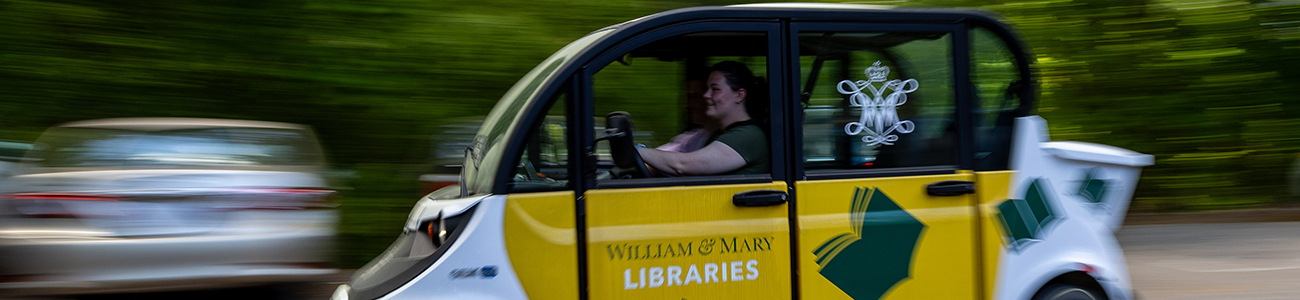 Student driving the library delivery cart with the background blurred to show motion