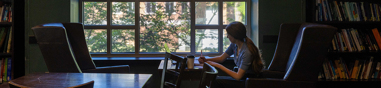 Student studying in front of a brightly lit window in Swem's 24 Hour Study Lounge