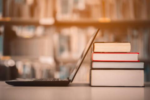 Open laptop resting against a stack of books.