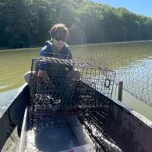 Person on a small boat with a fishing cage