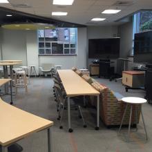 Cox Classroom with desks set up looking at two screens and a couch in front of the desks