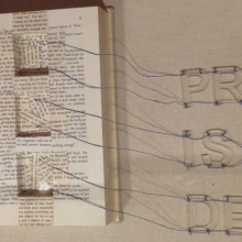 Open book with three square sections cut out. Strings from the cut-outs spell the words Print is Dead