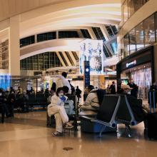 An airport terminal with passengers seated and walking.