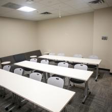 View to the back of the Kyle Classroom with three white tables and 12 chairs