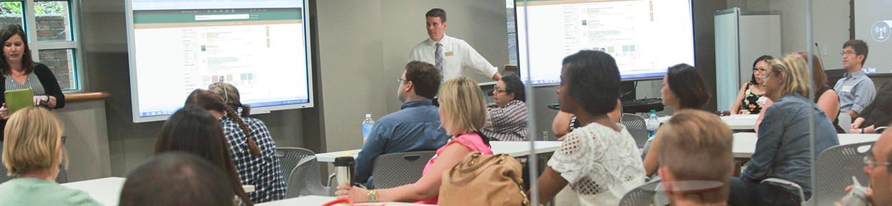 A Librarian in the background leads a class of students through an instruction session