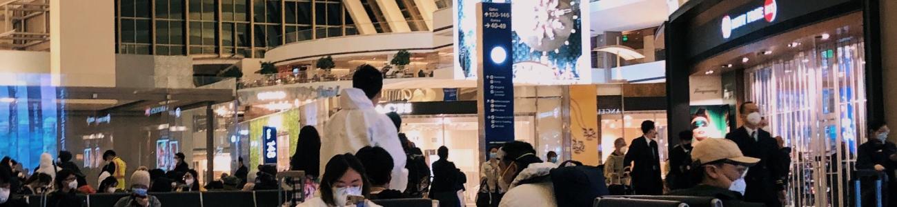 An airport terminal with passengers seated and walking.