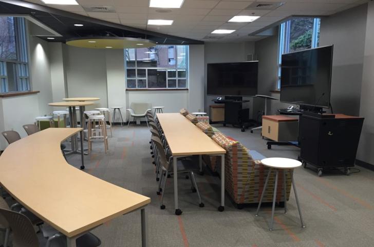 Cox Classroom with desks set up looking at two screens and a couch in front of the desks