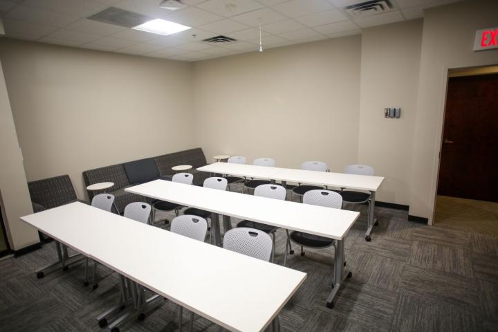 View to the back of the Kyle Classroom with three white tables and 12 chairs