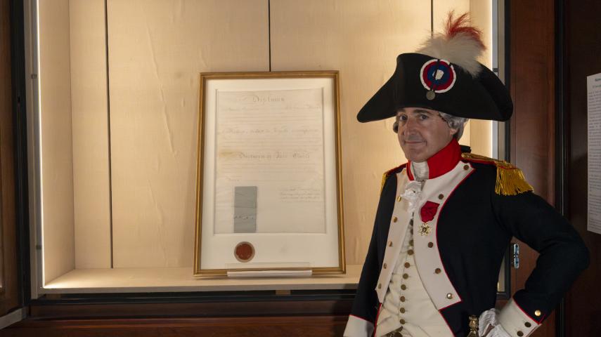 Lafayette re-enactor dressed in historical French uniform standing next to the diploma in Special Collections.