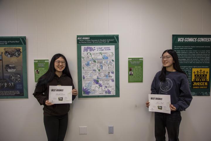 Kara and Rachel smile proudly in front of their work on display