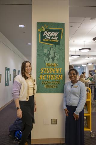 The creators of the comics contest, Rachel and Liz, stand proudly in front of the title display of the exhibit
