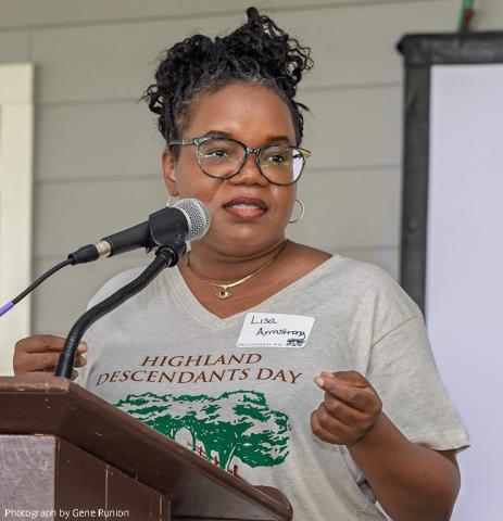 Black woman at podium, shirt reading Highland Descendants Day