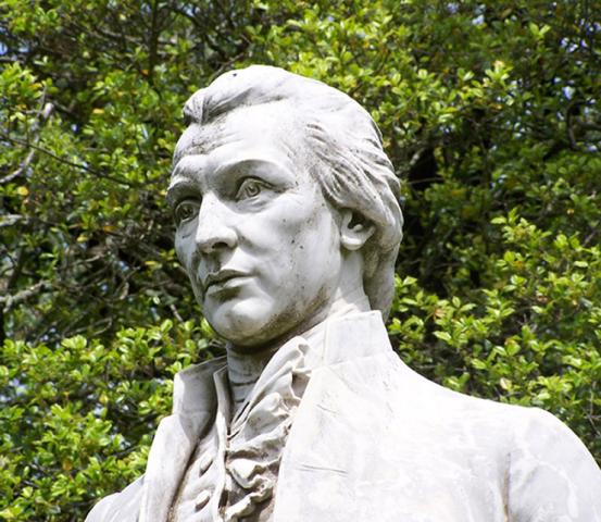Grey stone statue of a young James Monroe from shoulders up.