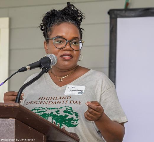 Black woman at podium, shirt reading Highland Descendants Day