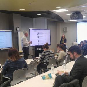 Presentation in the Ford Classroom with a presenter surrounded by two digital displays and audience seated in chairs