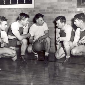 Historic photo of basketball players kneeling in discussion