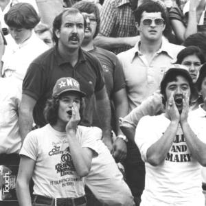 A black and white photo of a crowd of people with two individuals in the foreground.