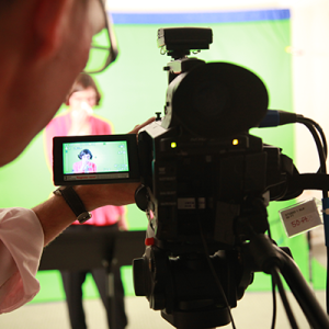Closeup of the viewfinder on a video camera displaying a person on a green screen