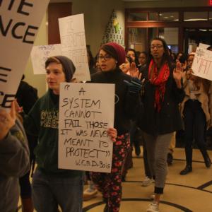 Students holding protest signs as part of a walk-in of Swem Library