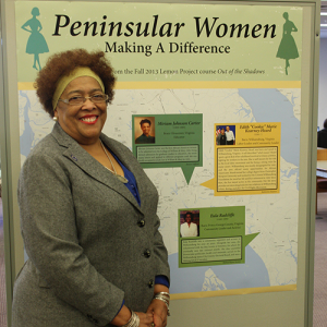 Edith Heard standing in front of a display that reads "Peninsular Women Making a Difference"