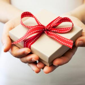 two hands holding a small gift box with a red bow