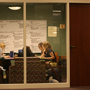 Students working together in a study room with a large whiteboard