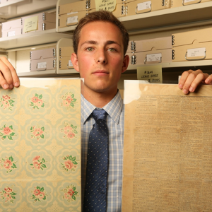Person holding up two pages from an archive collection