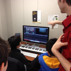 Students work on editing a video in a media studio