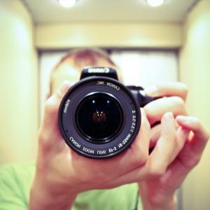 Closeup of a person holding a camera pointing forward at the viewer