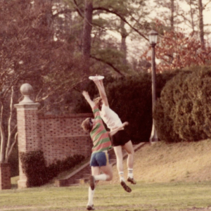 Two people jump to catch a frisbee in the Sunken Garden