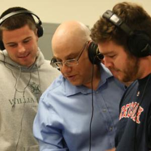 Three people wearing headphones work on a synthesizer