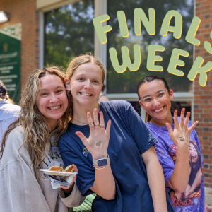 Students smiling and showing off hands with stamps from finals week activities
